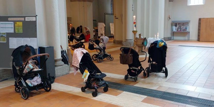 Eine Reihe von Kinderwägen, abgestellt im Kirchenvorraum. Sankt Anna, München